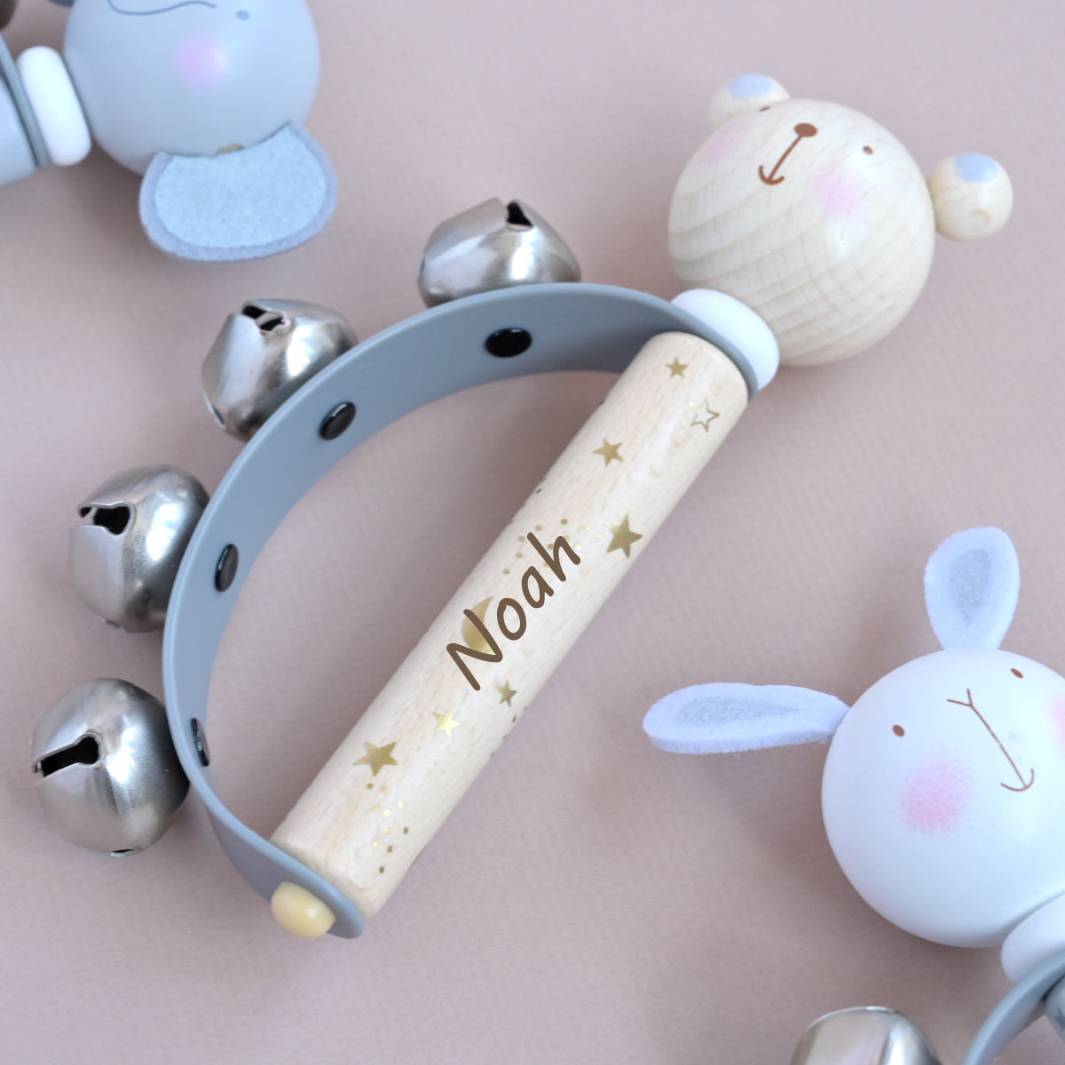 Personalised wooden teddy hand bells with wooden bear face, engraved name 'Noah', and decorative stars and bells.