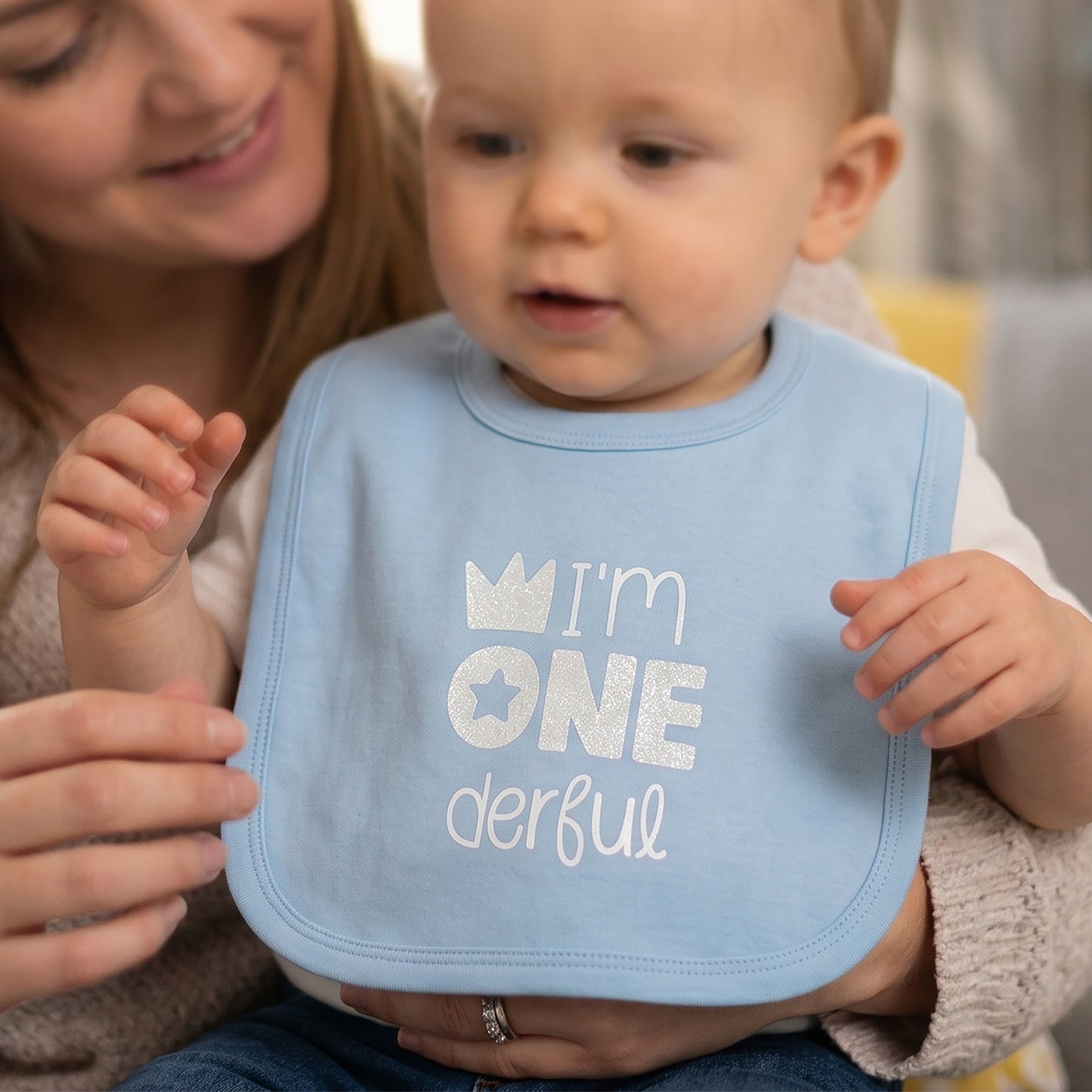 Pale blue 1st birthday baby bib with silver glitter "I'm ONEderful" print, crown and star design