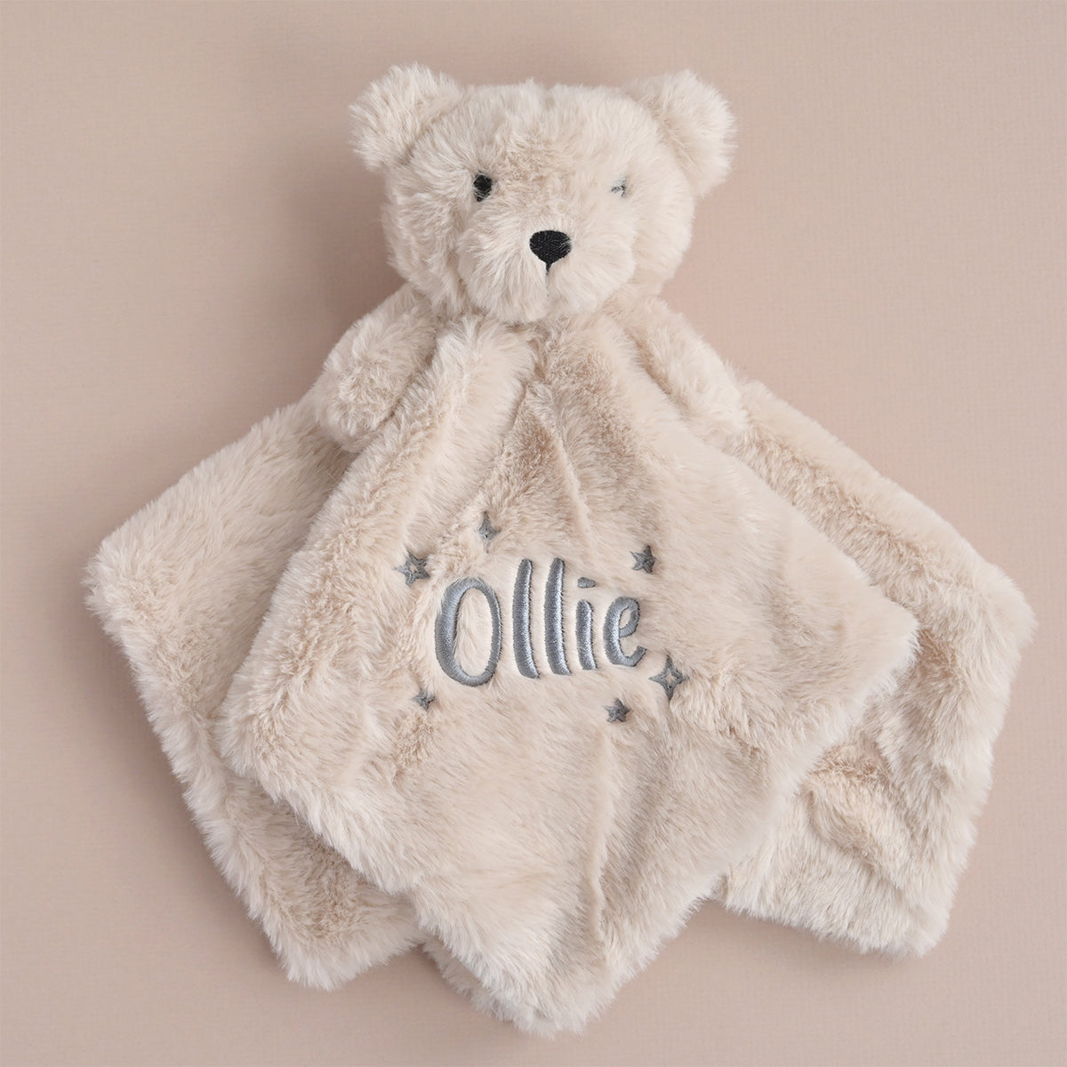  a soft beige faux fur teddy comforter, personalised with the name "Ollie" and embroidered grey stars.