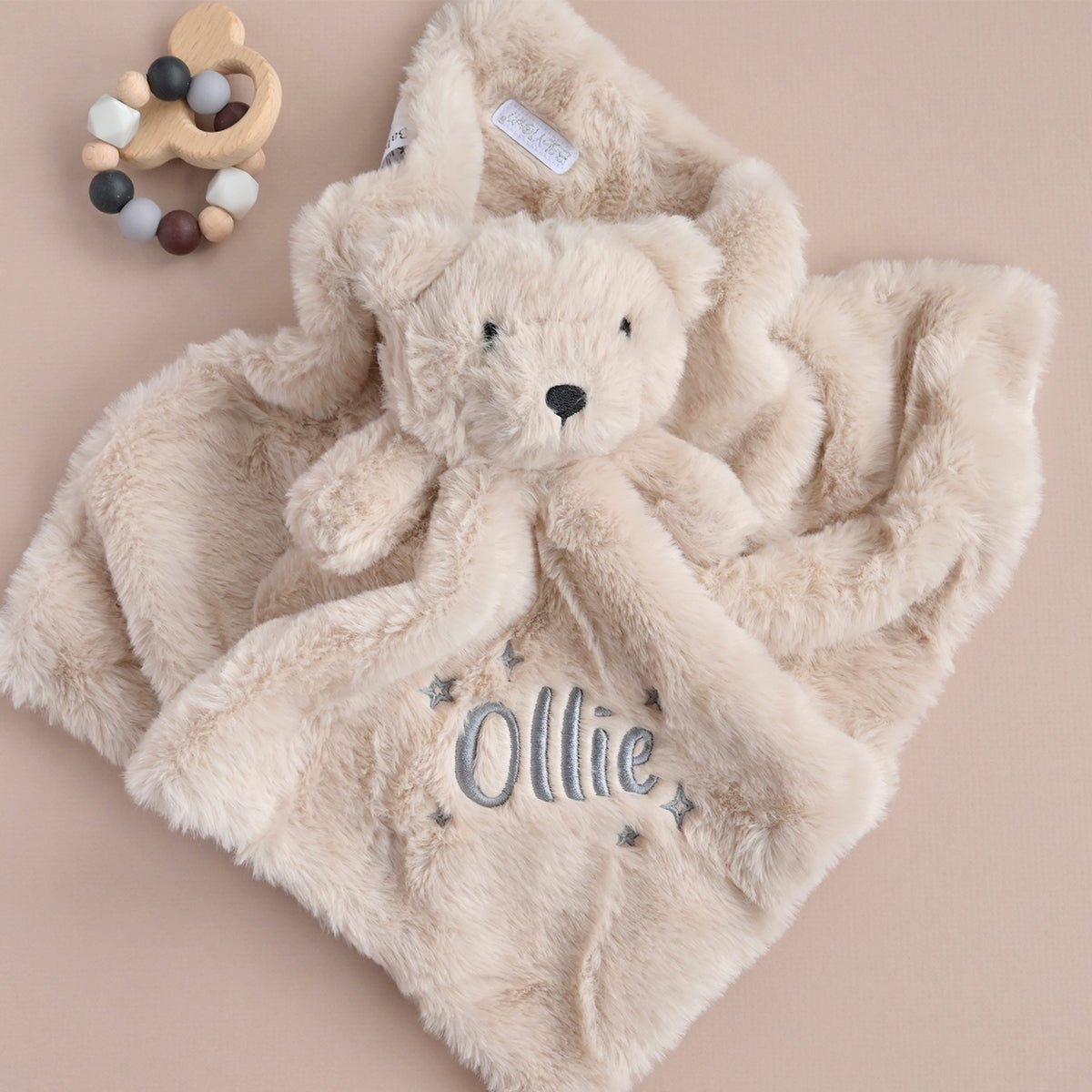 beige faux fur teddy comforter, personalised with the name "Ollie" and embroidered grey stars.