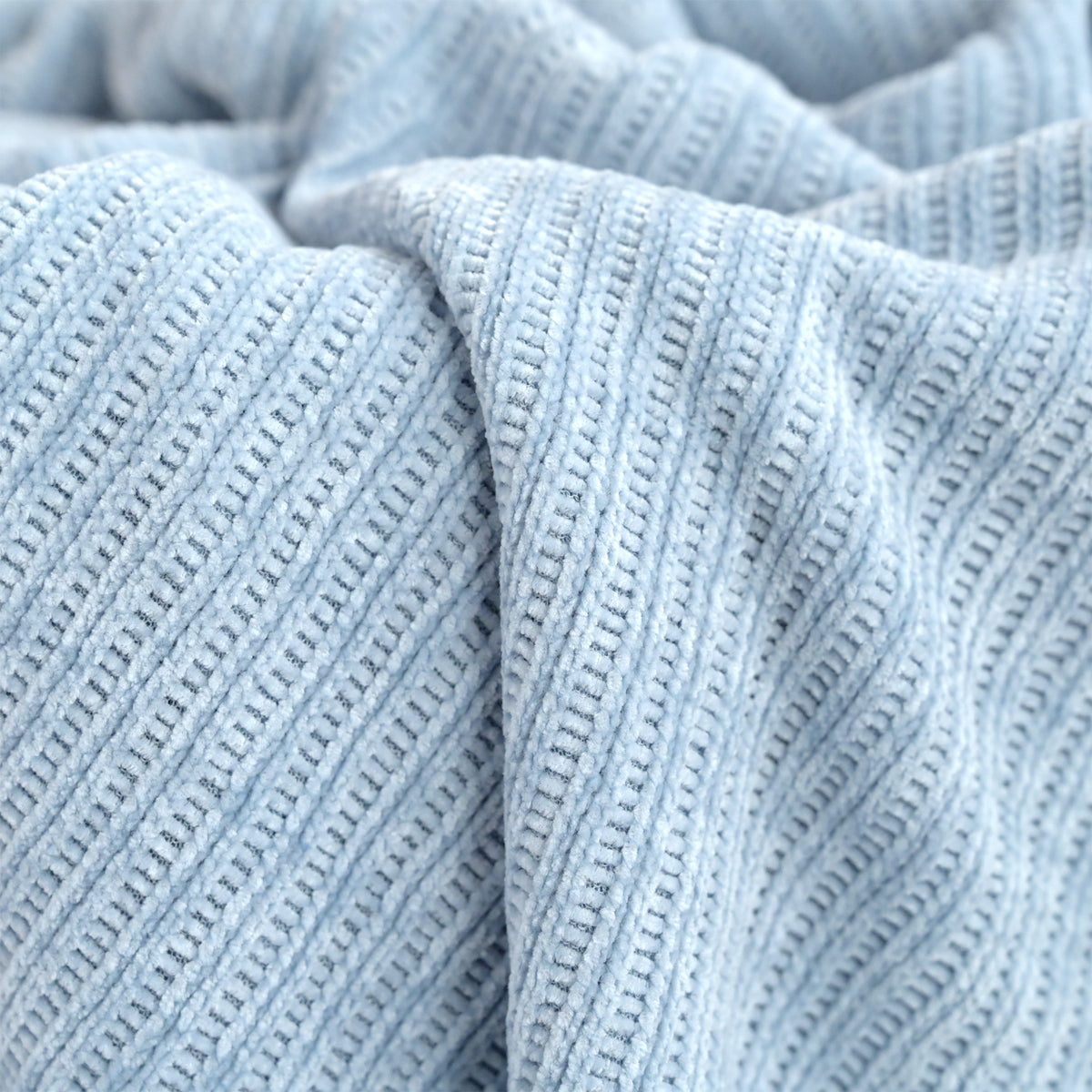 A close-up of light blue ribbed knit fabric with a textured woven pattern, shown in soft folds.
