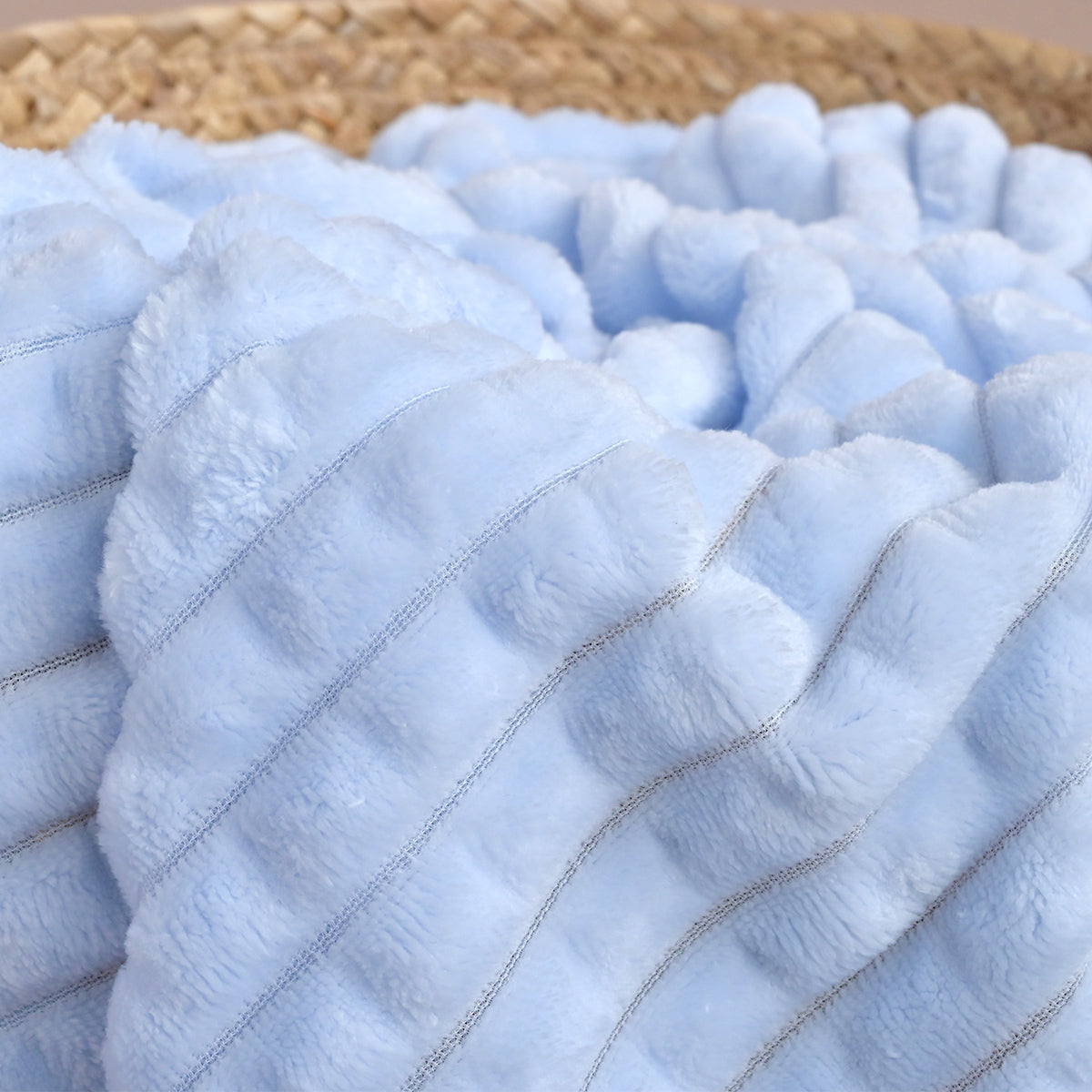Close-up of blue ribbed fleece fabric folded to show the diagonal quilted texture in detail.