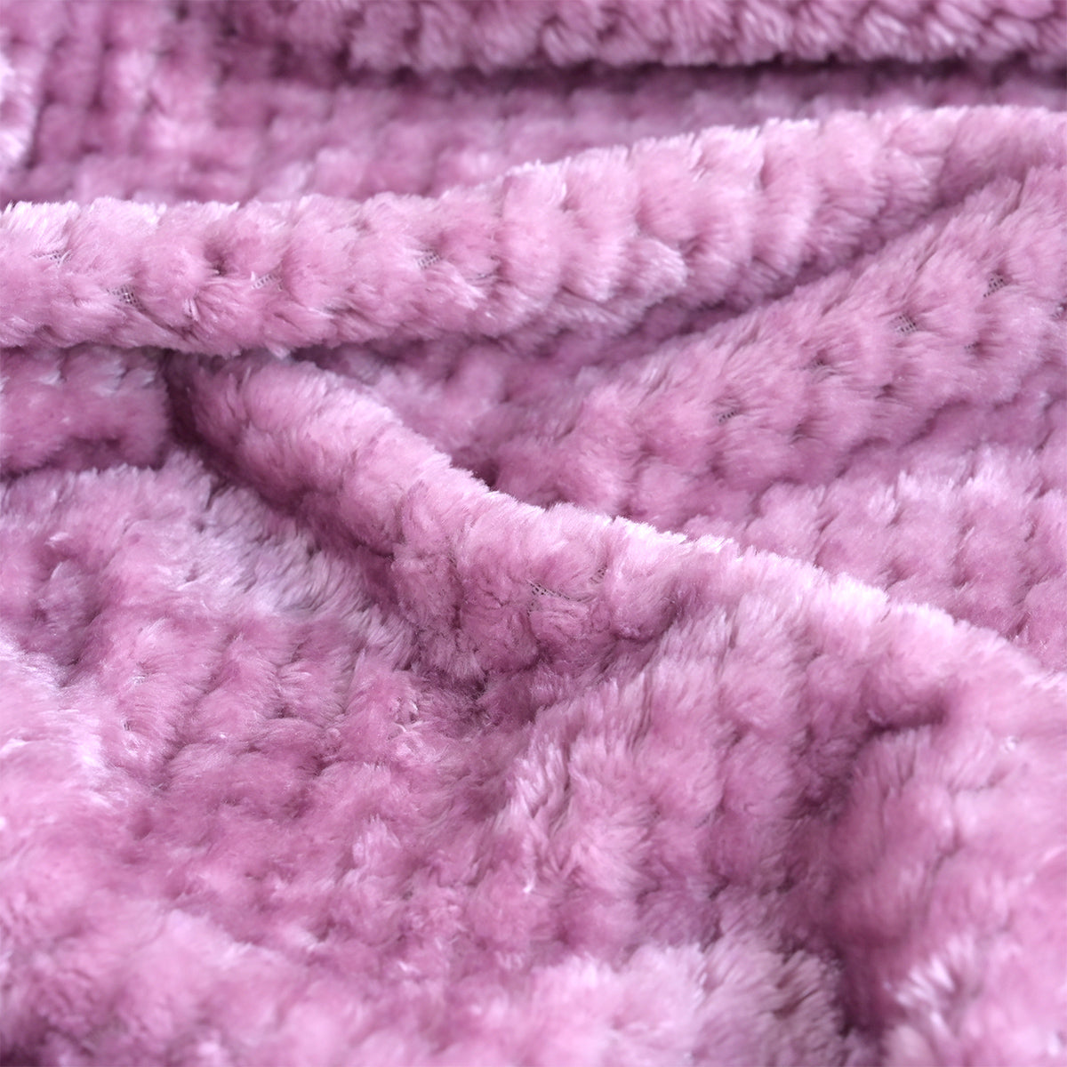 A close-up of a soft, plush pink blanket with a textured, looped surface, shown draped in folds.