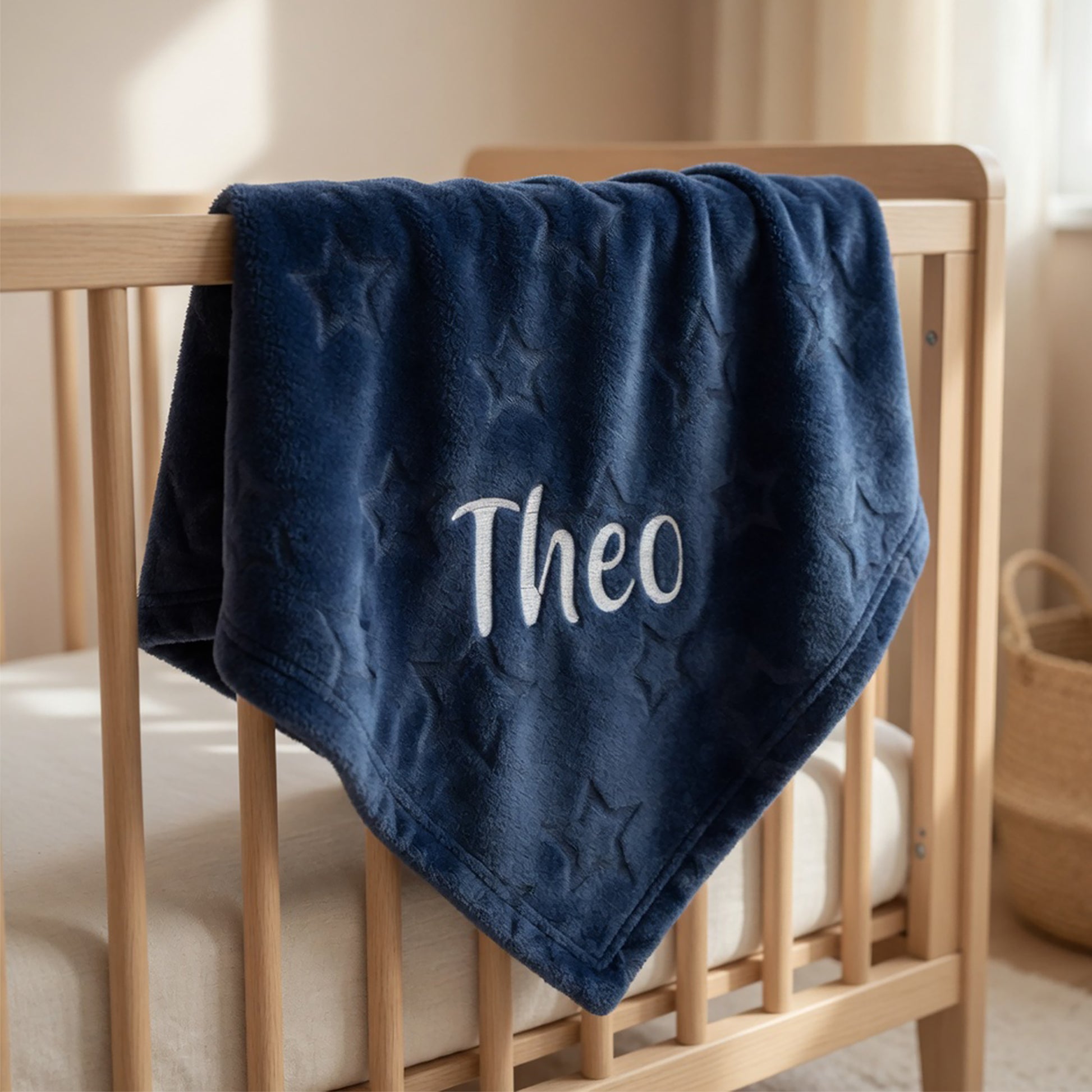 Navy blue blanket with 'Theo' embroidered on a wooden crib