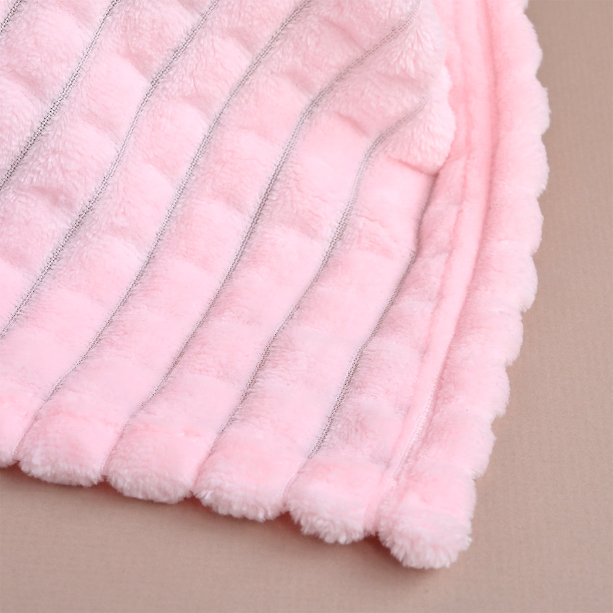 Close-up of pink ribbed fleece fabric folded to show the diagonal quilted texture in detail.