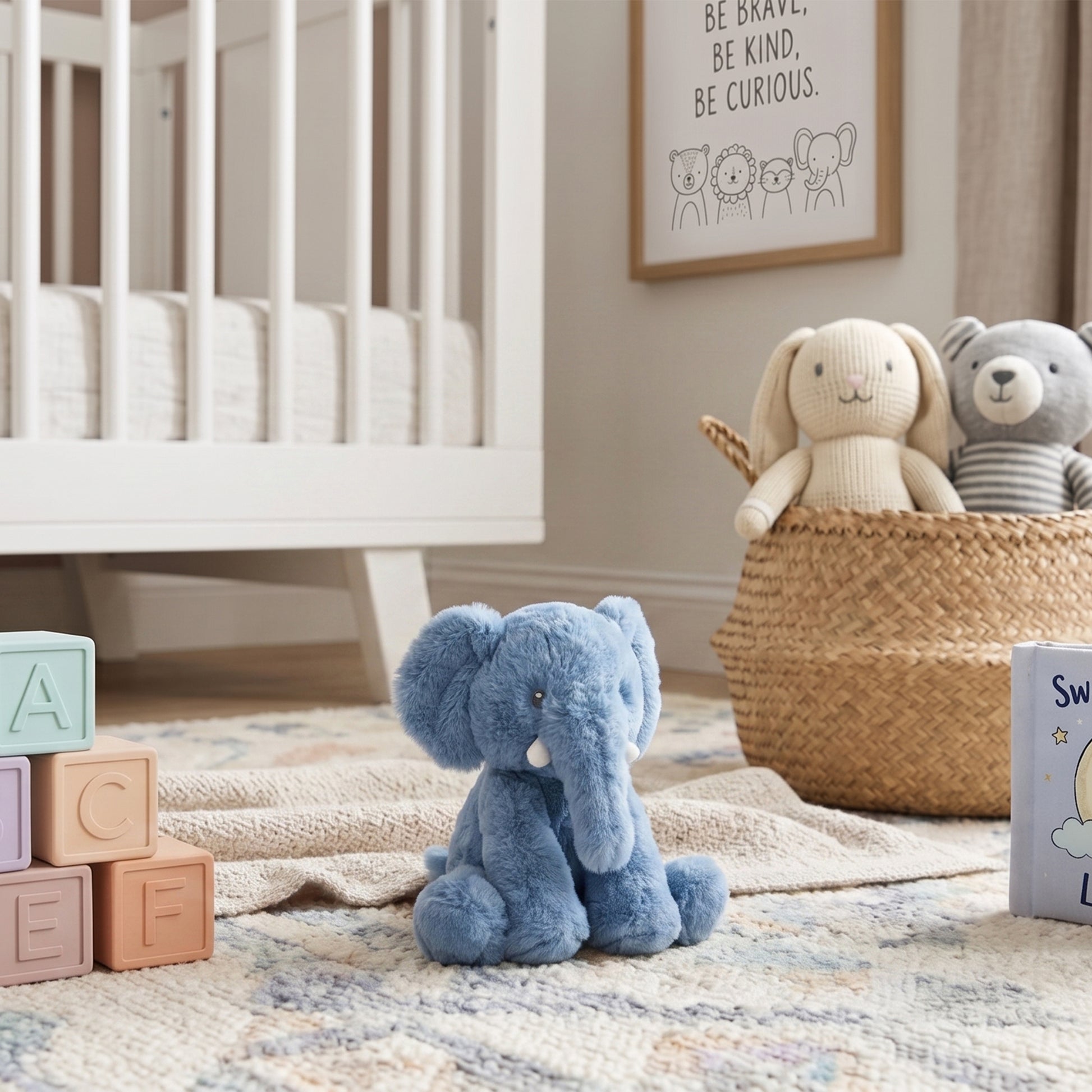 Small blue recycled fabric elephant soft toy sitting on a nursery rug next to wooden alphabet blocks.