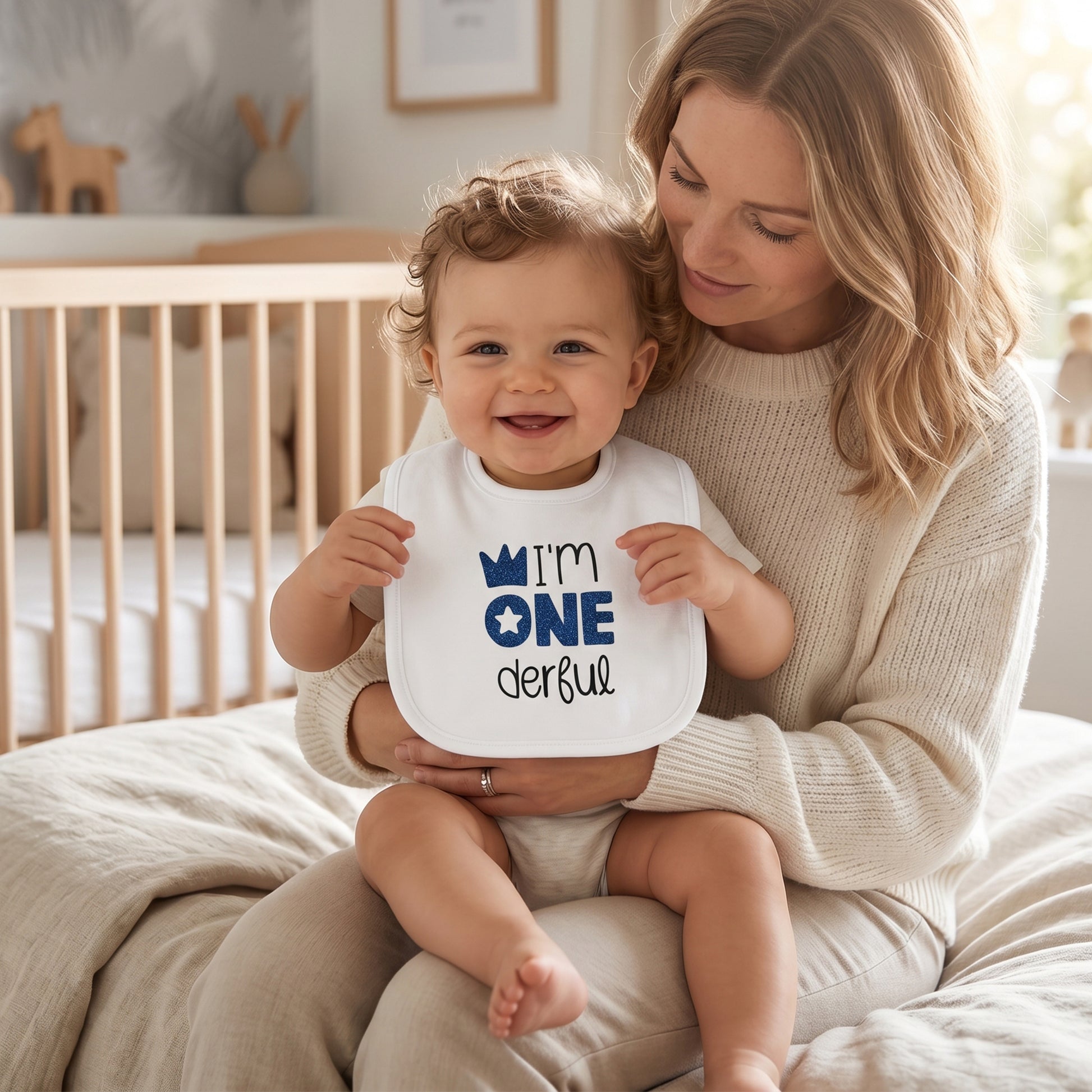 White 1st birthday baby bib with navy glitter "I'm ONEderful" print, crown and star design